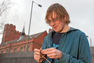 University of Sheffield Student Alix Bodin knitting outside the University House with Firth Hall in the background 