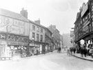 View: s19541 Snig Hill from Bridge Street. Premises include, No. 78 Boots Pure Drug Co., chemists and derelict timber framed shops prior to demolition, Right, premises include No 59, John W. Burrell, hosier