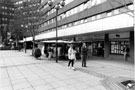 View: s23241 Nos. 110, Sew Fast, clothing alteration; 108, Sheffield Racial Equality Council, Community Relations Office and Moorfoot Market, The Moor with the Crucible Fountain Sculpture and Manpower Service Commission Building in the background