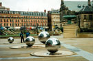 Stainless Steel Ball sculptures entitled Rain by Colin Rose, Millennium Square with the Peace Gardens and Pinstone Street in the background and the City Ambassadors on patrol