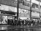 View: s35393 Bread queues outside G.H.Fletcher and Son, bakers, No.12 Exchange Street during the Bakery Strike showing also Henry Fields Ltd (No.10), ladies' sportswear and F.W. Woolworth and Co.Ltd