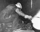 View: s40730 Billy Hart covers his face with gloved hand whilst he measures heavy armour plate with calipers whilst still red hot from the rolling mill