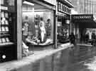 View: s44120 Eve Brown, costumier (No.19), William Timpson Ltd., shoe shop (No.21) and T. B. and W. Cockayne, department store, Market Place