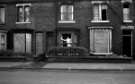 Woman cleaning her windows in unidentified derelict street, c.1970s