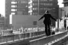 Man walking on railings on Arundel Gate subway showing (back) AEU House, offices, c.1970s