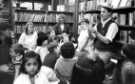 View: s46644 Nick Robinson, giving an origami demonstration, Central Children's Library, Central Library, Surrey Street showing also (centre back) Ann Ardron, library assistant and (centre right) Elaine Jones, library assistant